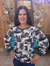 Load image into Gallery viewer, Someone standing with a top on that has rodeo horses on it. It has dots on the trim of the neck and arms.
